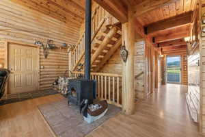 Interior space with a wood stove, wooden ceiling, beam ceiling, wood-type flooring, and rustic walls