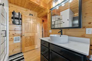 Bathroom with wood walls, hardwood / wood-style flooring, wooden ceiling, beam ceiling, and vanity