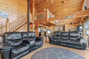 Living room featuring high vaulted ceiling, light hardwood / wood-style floors, wooden ceiling, and wood walls