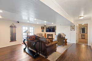 Living room featuring crown molding, a textured ceiling, and hardwood / wood-style floors