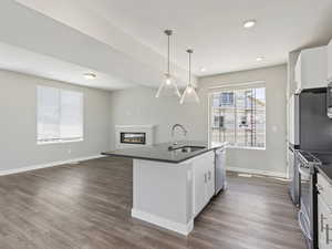 Kitchen with a center island with sink, sink, white cabinetry, and dark hardwood / wood-style floors