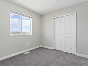 Unfurnished bedroom featuring a closet and dark colored carpet