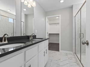 Bathroom with walk in shower, double sink, tile floors, and vanity with extensive cabinet space