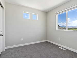 Unfurnished room with a healthy amount of sunlight and dark carpet