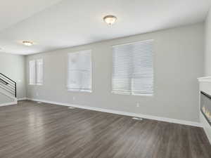 Unfurnished living room featuring dark wood-type flooring