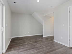 Additional living space with dark hardwood / wood-style floors and vaulted ceiling