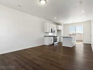 Unfurnished living room featuring sink and dark hardwood / wood-style flooring