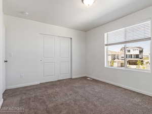 Unfurnished bedroom with a closet, multiple windows, and carpet floors