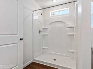 Bathroom with a shower, wood-type flooring, and a textured ceiling