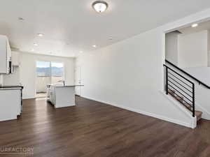 Kitchen featuring sink, white cabinets, a kitchen island with sink, and dark wood-type flooring