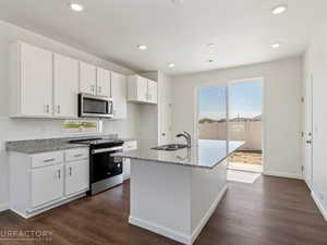 Kitchen featuring stainless steel appliances, an island with sink, a wealth of natural light, and dark hardwood / wood-style floors