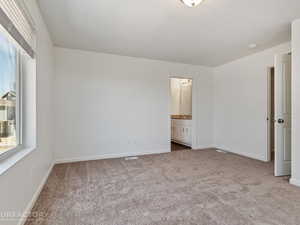 Unfurnished bedroom with ensuite bathroom and carpet flooring