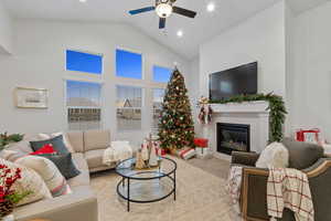 Carpeted living room with high vaulted ceiling, a brick fireplace, and ceiling fan