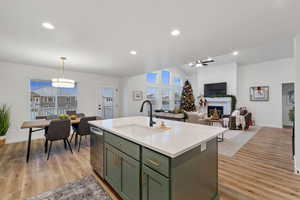 Kitchen featuring an island with sink, sink, light hardwood / wood-style floors, and stainless steel dishwasher