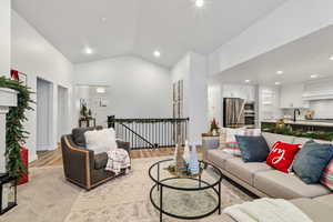 Carpeted living room with sink and lofted ceiling