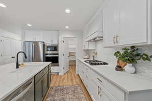 Kitchen with backsplash, white cabinetry, and appliances with stainless steel finishes