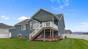 Rear view of house featuring a wooden deck and a lawn