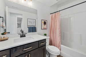 Full bathroom with a textured ceiling, toilet, vanity, and shower / bath combo