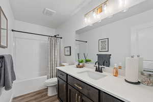 Full bathroom with toilet, wood-type flooring, oversized vanity, and shower / tub combo with curtain