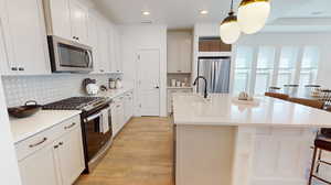 Kitchen with stainless steel appliances, an island with sink, decorative light fixtures, backsplash, and sink