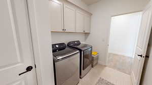 Clothes washing area with cabinets, light tile floors, and upper cabinets