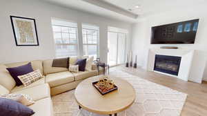 Living room with a tray ceiling and light wood-type flooring