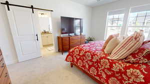 Carpeted bedroom with a barn door, and ensuite bath