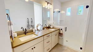 Bathroom with dual sinks, a shower with door, tile floors, and large vanity