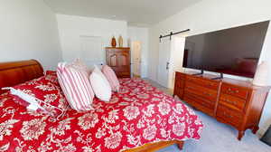 Carpeted bedroom featuring a barn door to the bathroom