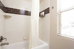 Bathroom featuring a healthy amount of sunlight and shower / bath combo with shower curtain