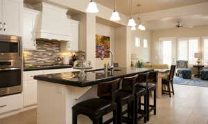 Kitchen with an island with sink, stainless steel appliances, premium range hood, white cabinets, and a kitchen bar