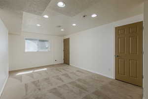 Empty room with light carpet and a textured ceiling