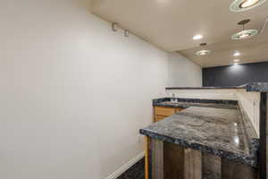 Kitchen with dark stone counters, dark tile flooring, and sink