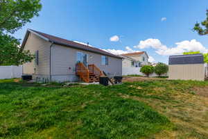 Rear view of house with a shed, central AC, and a yard