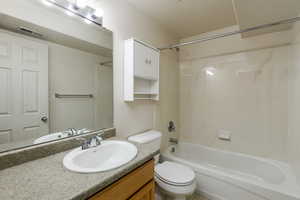 Full bathroom featuring a textured ceiling, vanity, toilet, and bathtub / shower combination