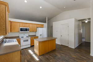 Kitchen featuring white appliances, sink, dark hardwood / wood-style floors, and a kitchen island