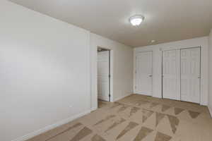 Unfurnished bedroom featuring a textured ceiling, a closet, and light colored carpet