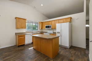 Kitchen with a center island, high vaulted ceiling, dark hardwood / wood-style flooring, and white appliances