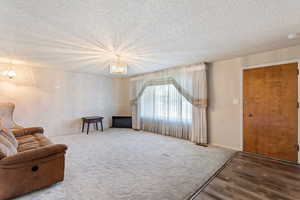 Living area with a textured ceiling, an inviting chandelier, and hardwood / wood-style floors