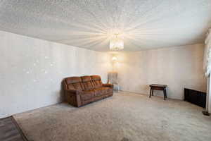 Sitting room featuring a notable chandelier, carpet, and a textured ceiling