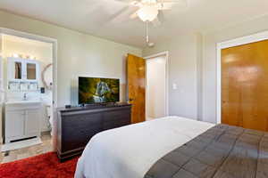 Bedroom with ceiling fan, hardwood / wood-style flooring, connected bathroom, and sink