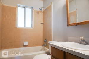 Full bathroom with a healthy amount of sunlight, vanity, toilet, and tiled shower / bath combo