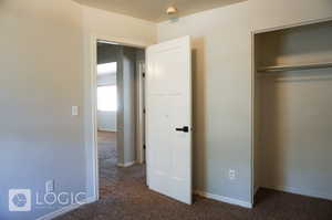 Unfurnished bedroom featuring a closet and dark colored carpet