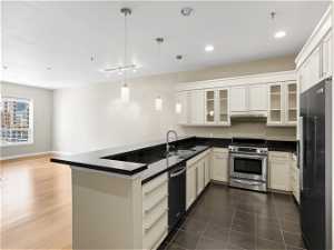 Kitchen featuring hanging light fixtures, dark hardwood / wood-style floors, kitchen peninsula, high end appliances, and sink
