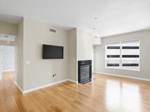 Unfurnished living room featuring a high end fireplace and light wood-type flooring