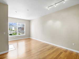 Empty room with light hardwood / wood-style floors and rail lighting