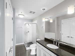 Bathroom featuring tile flooring, oversized vanity, an enclosed shower, and toilet