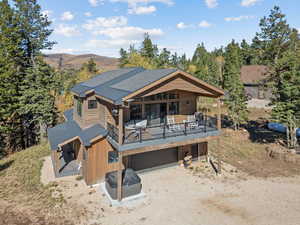Rear view of house with dirt driveway, a deck, and a garage