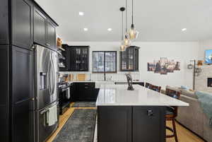 Kitchen featuring sink, a breakfast bar area, appliances with stainless steel finishes, light stone counters, and a kitchen island