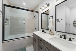 Bathroom featuring vanity and bath / shower combo with glass door